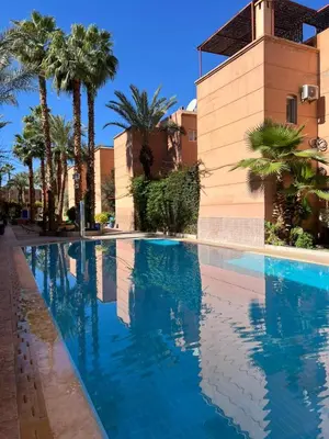 a swimming pool in front of a building with palm trees at Riad 49 G26 in Marrakech