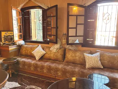 a brown leather couch in a room with windows at Maison de Vacances Idéale à 10 min de l'Aéroport in Marrakech