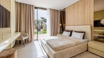 a bedroom with a bed and a desk and a window at Villa jardin atlas in Marrakech