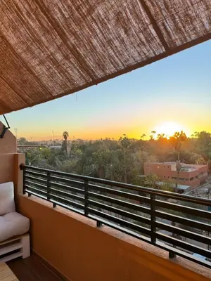 a balcony with a view of the sunset at KL Home- au cœur du centre ville moderne in Marrakech