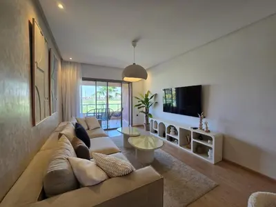 a living room with a large couch and a tv at Appartement Cosy - vue Piscine - Prestigia JADE in Marrakech