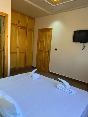 a bedroom with a bed with white sheets and a tv at Villa Soufia in Marrakech