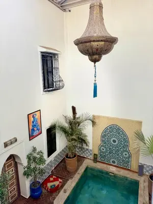 a swimming pool in a room with a chandelier at Riad FARASHA in Marrakech