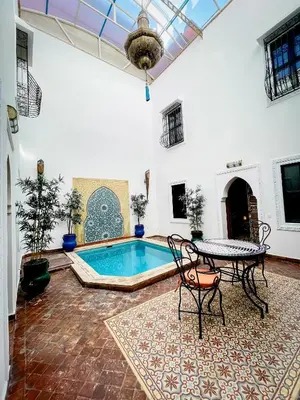 a pool in a room with a table and chairs at Riad FARASHA in Marrakech