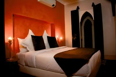 a bedroom with a large bed with an orange wall at Riad FARASHA in Marrakech