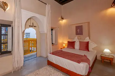 a bedroom with a bed with red pillows and a window at Riad GUENAOUA in Marrakech