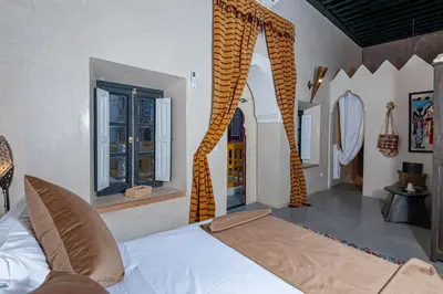 a bedroom with a bed and a room with windows at Riad GUENAOUA in Marrakech