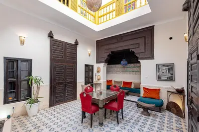 a living room with a table and red chairs at Riad GUENAOUA in Marrakech