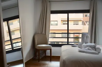 a room with a bed and a chair and a window at Duplex Safiya Suites and Services in Marrakech