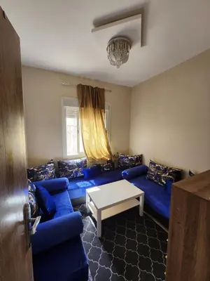 a living room with a blue couch and a table at Comfortable apartment near the Airport in Marrakech