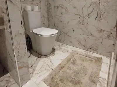 a bathroom with a toilet and a marble wall at Marrakech Luxury ATLAS in Marrakech