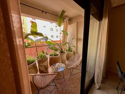 a table with chairs and potted plants on a balcony at Appartement idyllique au centre ville in Marrakech