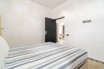 a bedroom with a bed with a blue and white striped blanket at Villa Slimani in Marrakech