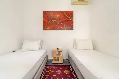 two beds in a room with a painting on the wall at Villa Slimani in Marrakech