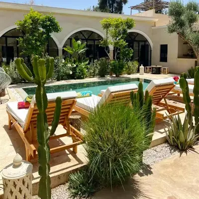 a backyard with a swimming pool with chairs and cactus at Run Villa Marine, Elegant Private Villa in Marrakech with Heated Pool Option in Marrakech