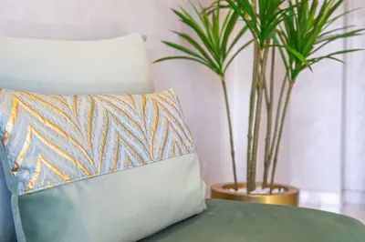 a couch with a pillow and two potted plants at Cocon Chaleureux au Cœur de la Ville in Marrakech