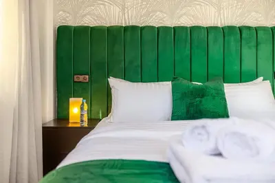 a bed with a green headboard with towels on a table at Cocon Chaleureux au Cœur de la Ville in Marrakech