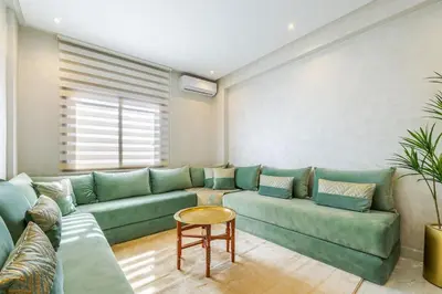 a living room with a green couch and a table at Cocon Chaleureux au Cœur de la Ville in Marrakech