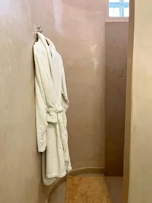 a white robe hanging on a wall in a bathroom at Palais Debora in Marrakech