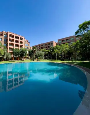 a large pool of blue water in front of buildings at Hivernage appartement premium in Marrakech