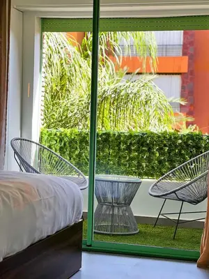 a room with a bed and two chairs outside a window at Hivernage appartement premium in Marrakech