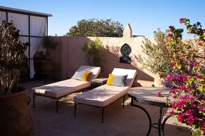 a patio with two chairs and a table and flowers at superbe riad en exclusivité B&B in Marrakech