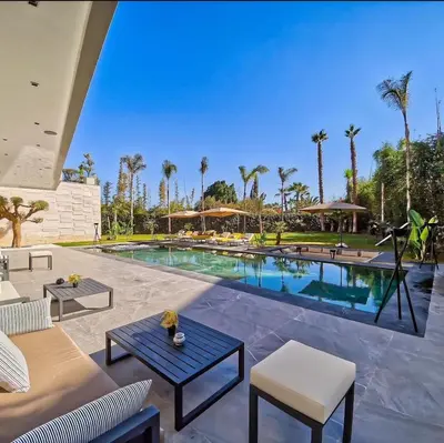 a pool with tables and chairs and palm trees at Villa Beverly hills-luxury home in Marrakech