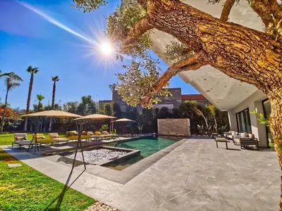 a house with a swimming pool and a tree at Villa Beverly hills-luxury home in Marrakech
