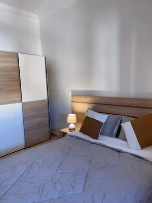 a bedroom with a large bed with a blue blanket and pillows at Bel appartement moderne in Marrakech