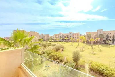 a balcony with a view of a park with palm trees at New! Appt Moderne Jubaea avec parking & wifi in Marrakech