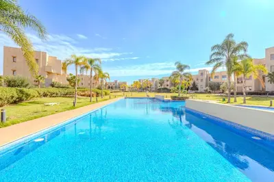 a large swimming pool with palm trees and buildings at New! Appt Moderne Jubaea avec parking & wifi in Marrakech