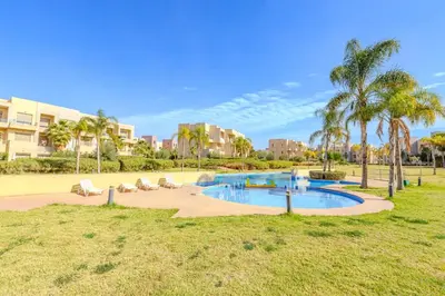 a swimming pool in a park with palm trees at New! Appt Moderne Jubaea avec parking & wifi in Marrakech
