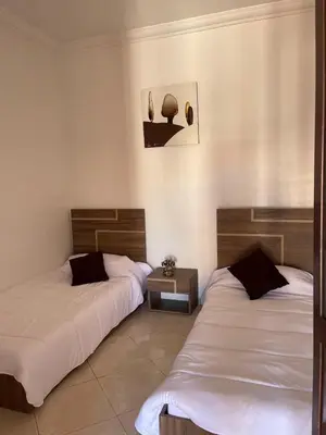 a room with two beds and a side table at Abwab guilize Beautiful modern apartment in Marrakech