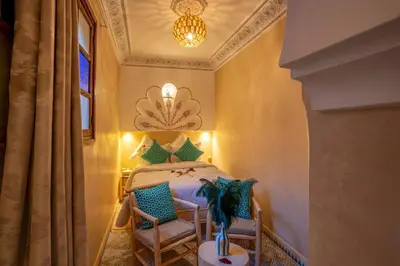 a bedroom with a bed with two chairs and a chandelier at Riad Le Graff Pink group in Marrakech