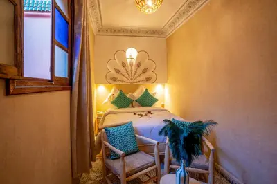 a bedroom with a bed and two chairs at Riad Le Graff Pink group in Marrakech