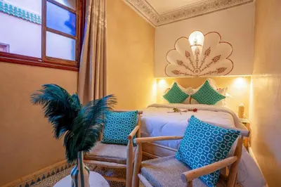 a bedroom with a bed with blue pillows and a window at Riad Le Graff Pink group in Marrakech