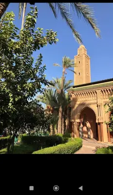 a building with a clock tower and palm trees at Riad Benhamou 3 in Marrakech
