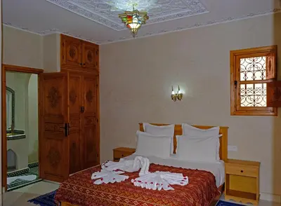 a bedroom with a bed with white sheets and a window at Riad Rose Mati in Marrakech