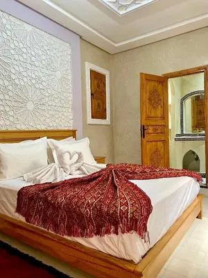 a bedroom with a large bed with a red blanket at Riad Rose Mati in Marrakech