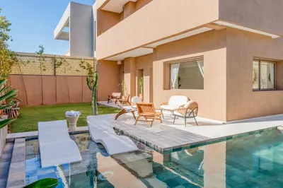 a backyard with a swimming pool and chairs and a house at Perfect Villa, Heated Pool, 15min from City Center, 4 Bedrooms, Private Cook and Airport Pickup in Marrakech