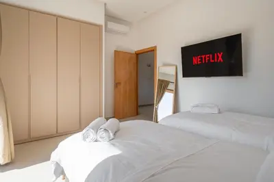 two beds in a room with a tv on the wall at Perfect Villa, Heated Pool, 15min from City Center, 4 Bedrooms, Private Cook and Airport Pickup in Marrakech