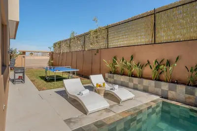 a patio with two chairs and a table and a pool at Perfect Villa, Heated Pool, 15min from City Center, 4 Bedrooms, Private Cook and Airport Pickup in Marrakech