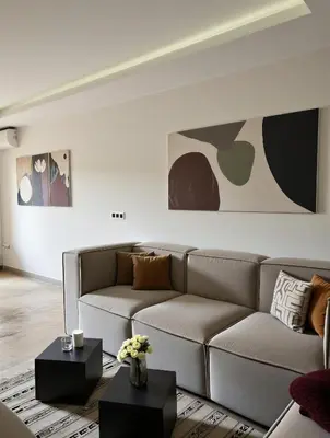 a living room with a couch and paintings on the wall at Bohemian Chic Duplex Marrakech in Marrakech