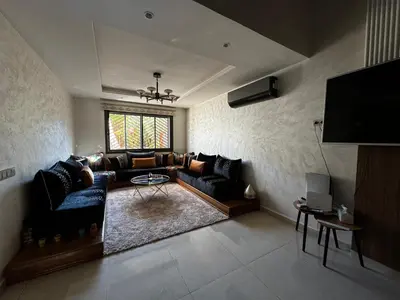 a living room with a couch and a tv at Duplexe super in Marrakech