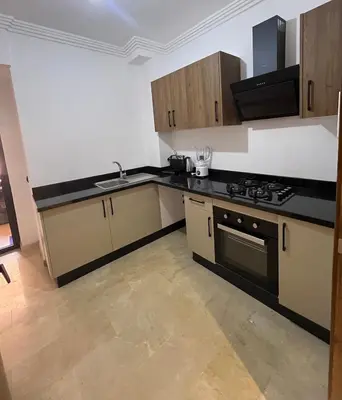a kitchen with wooden cabinets and a stove top oven at Cozy Apartment With Pool 5 min from Guéliz in Marrakech