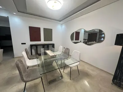 a room with a glass table and chairs and a mirror at Duplex spacieux avec jaccuzi in Marrakech