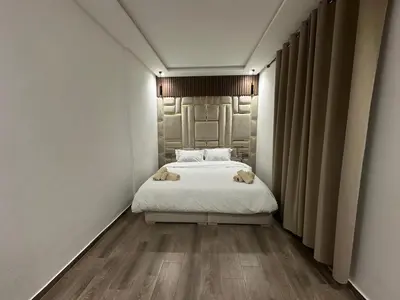 a bedroom with a white bed and a wooden floor at Duplex spacieux avec jaccuzi in Marrakech