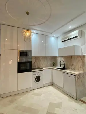 a kitchen with white cabinets and a washer and dryer at Gueliz ultra central & Cosy in Marrakech