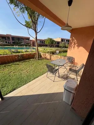a patio with a table and chairs on a deck at Rez de Jardin T3 Piscine Noria in Marrakech
