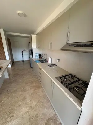 a kitchen with white cabinets and a stove top oven at Rez de Jardin T3 Piscine Noria in Marrakech